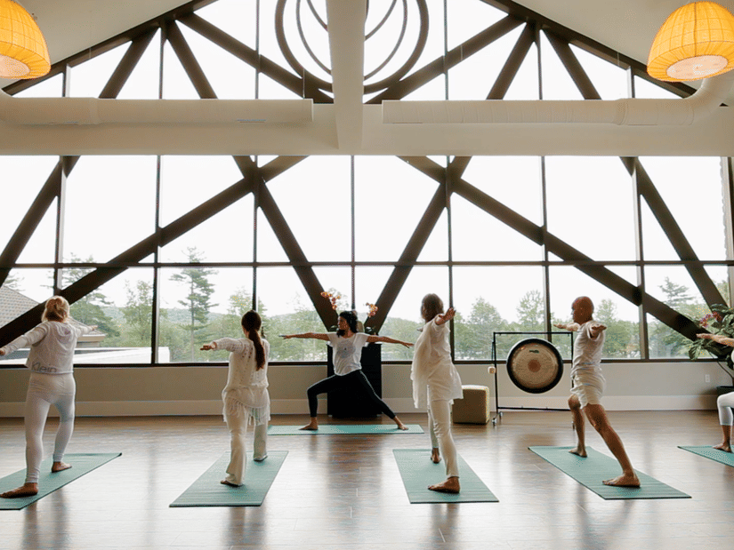 People performing yoga early in the morning inside a huge hall with the view of the outside at YO1 Longevity & Health Resorts, Catskills