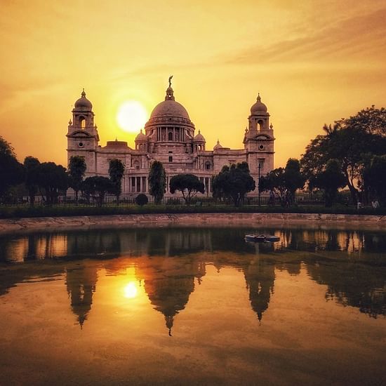 the facade of Victoria Memorial during evening time with the sun setting in the background