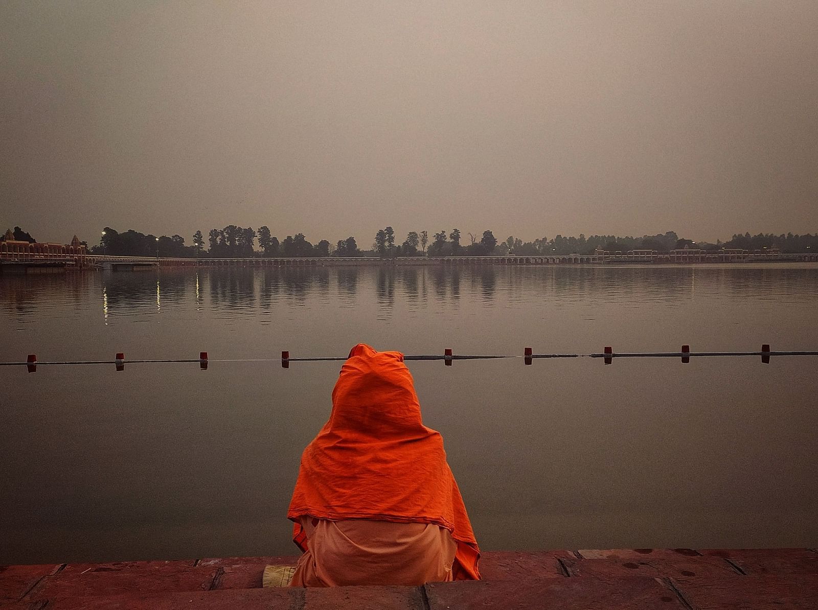 an image of a man sitting on the shore of a lake