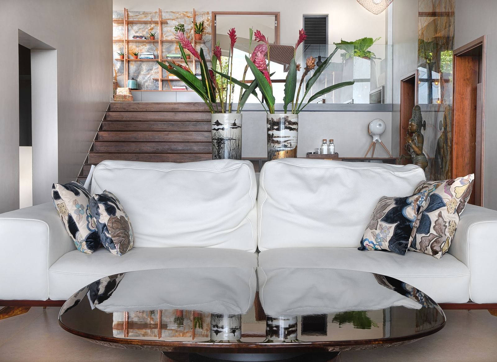 A seating area with a sofa and two large vases with flowers in the background at Stanley Revelation.