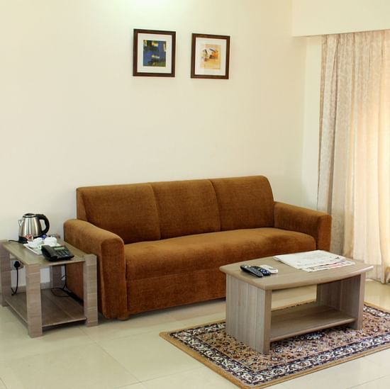 a living area featuring a sofa a coffee table a kettle and wall paintings - Maxxvalue Apartment Marol