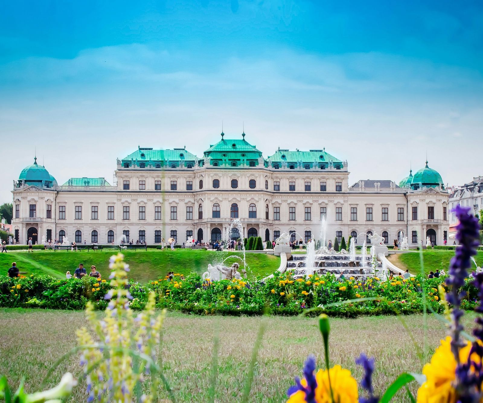 a far out view of a palace with a manicured garden in front of it