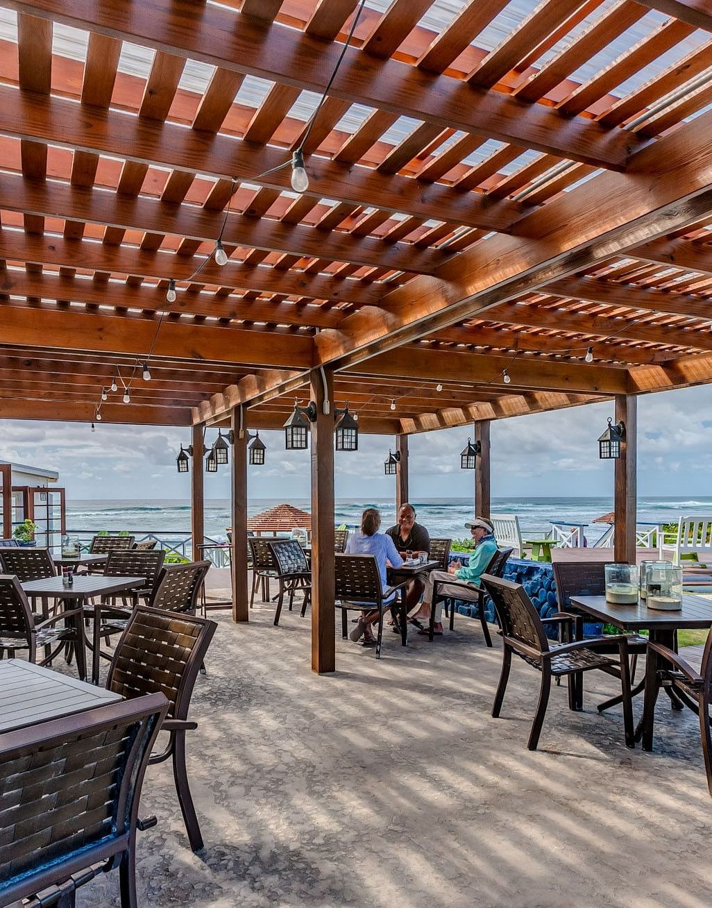 Outdoor dining space with wooden roof and tables | Abaco Inn