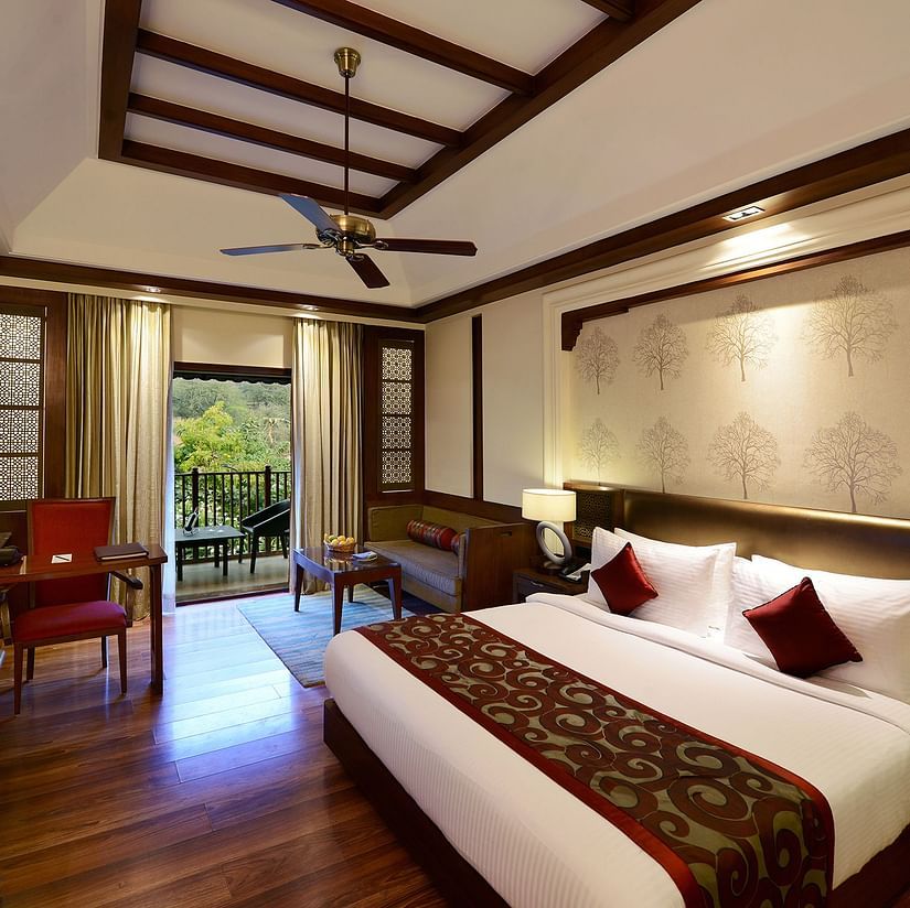 The interiors of our luxury cottages in Pushkar featuring a balcony, a comfortable bed, a desk and a television 