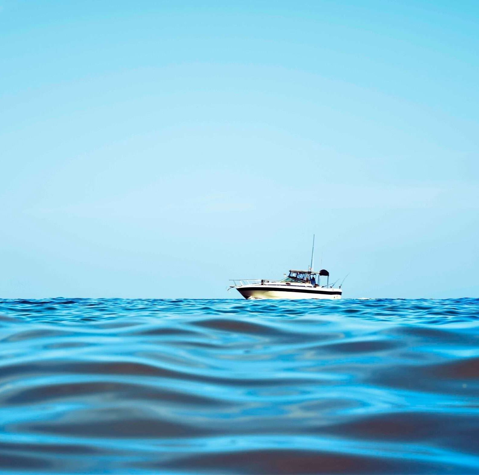 A wide angle shot of a cruise boat sailing in the sea featuring a clear blue sky in the background.