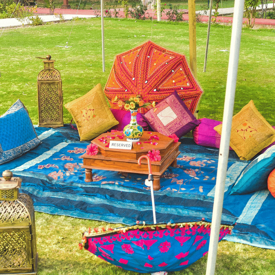 Colourful haldi or mehendi setup with vibrant cushions and décor at Umaid Palace lawn.