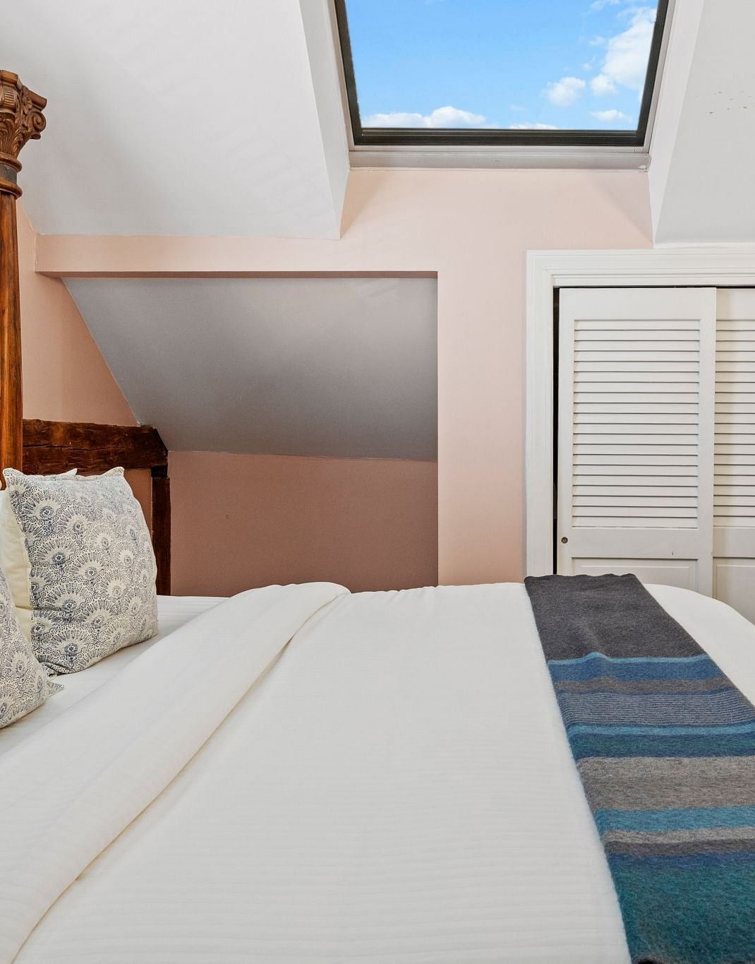 A bedroom with skylight, wicker headboard, and pastel walls at Hartstone Inn