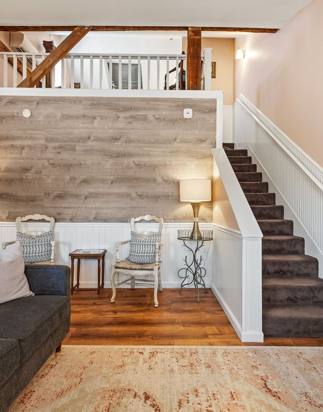 A room with sofa, wood accent wall, and stairway leading to loft at Hartstone Inn