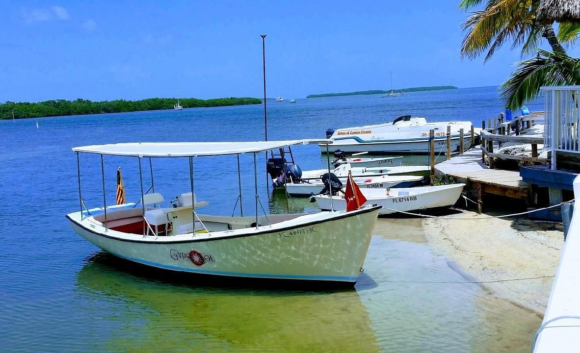 Boats moored on the shore at Casa Morada with clear skies, palm trees, and calm sea in the background.