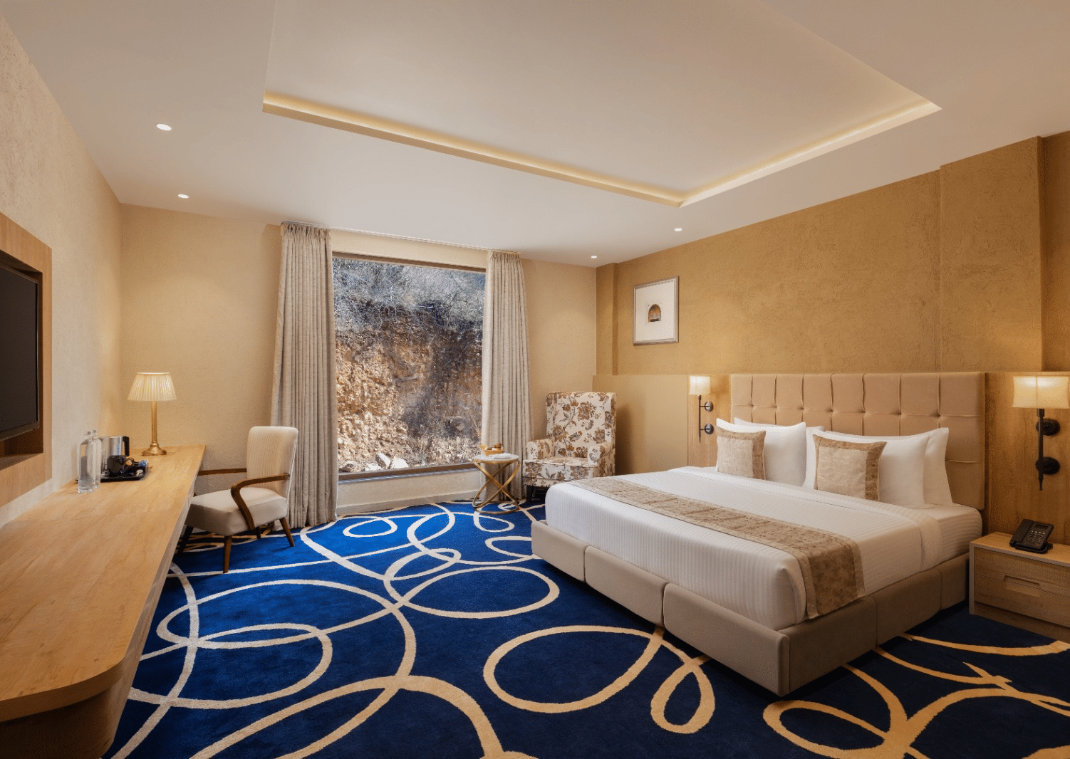 Superior room with king bed and blue accent rug at Essentia Luxury Resort & Spa, Udaipur.