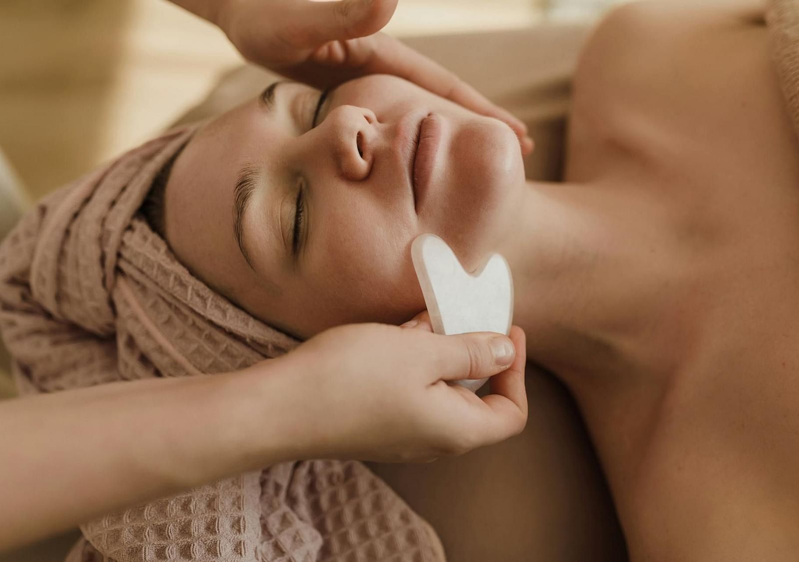 A lady receiving a face massage using a gua sha tool