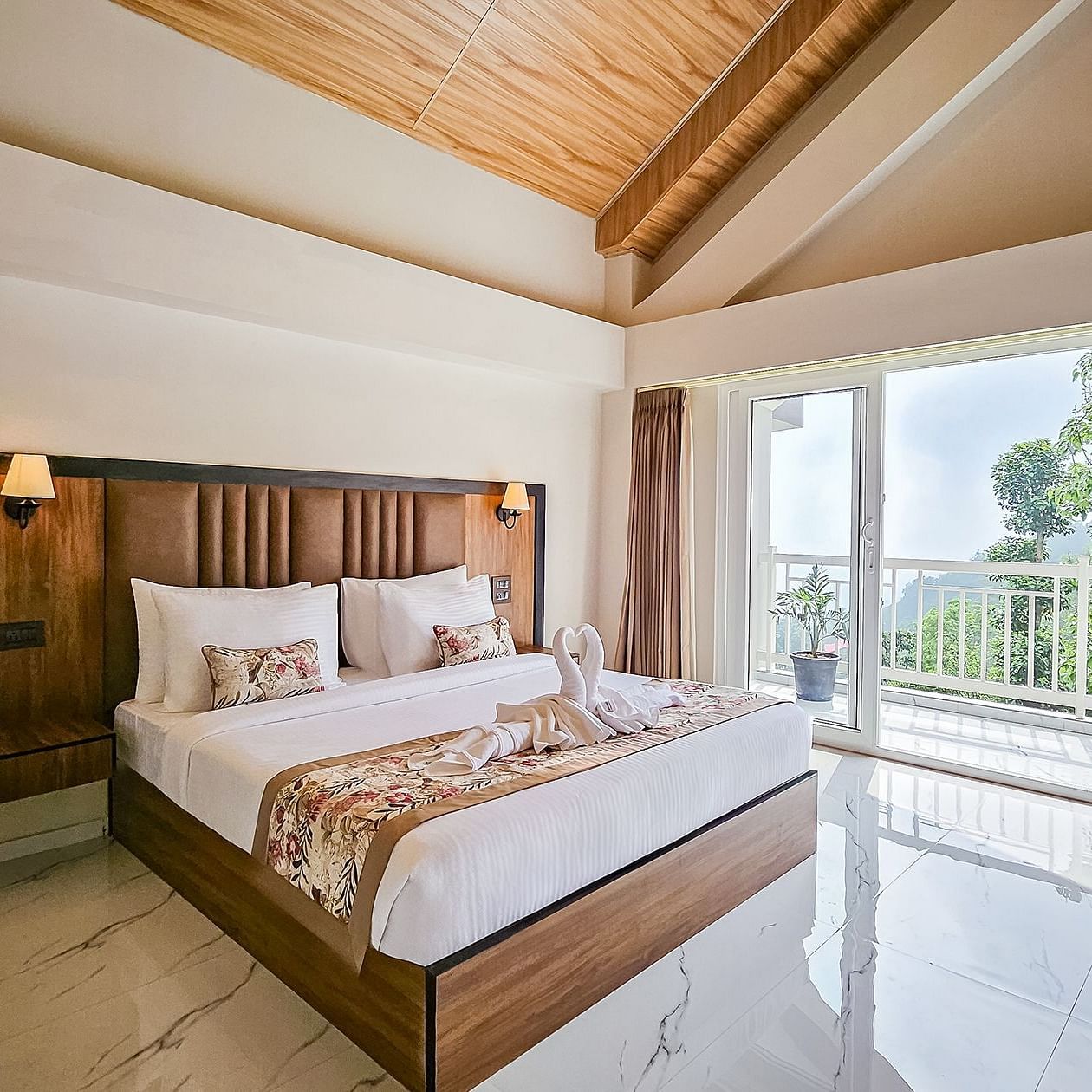  A well-lit bedroom at Yashshree Resort & Spa Kalimpong with a large bed, a wooden headboard, and a balcony offering a view of the outdoors.
