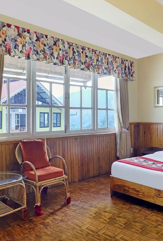 A room with a bed, chairs, and a glass window | Summit Newa Regency & Spa, Pelling