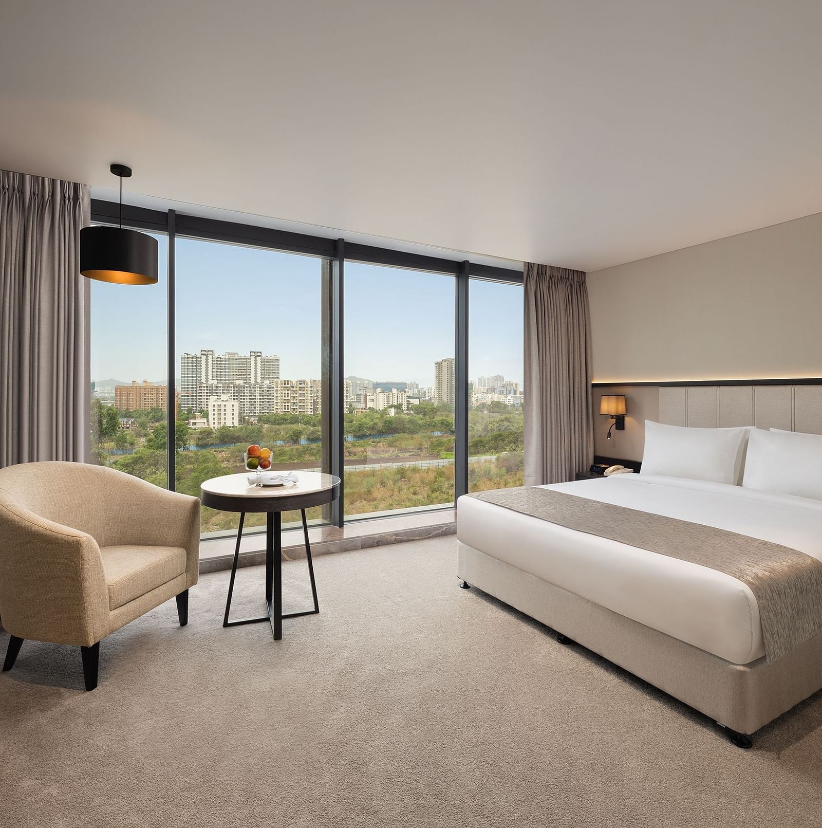  Premier Room with a king size bed and a sofa beside a large window at Essentia Premiere, Pune.