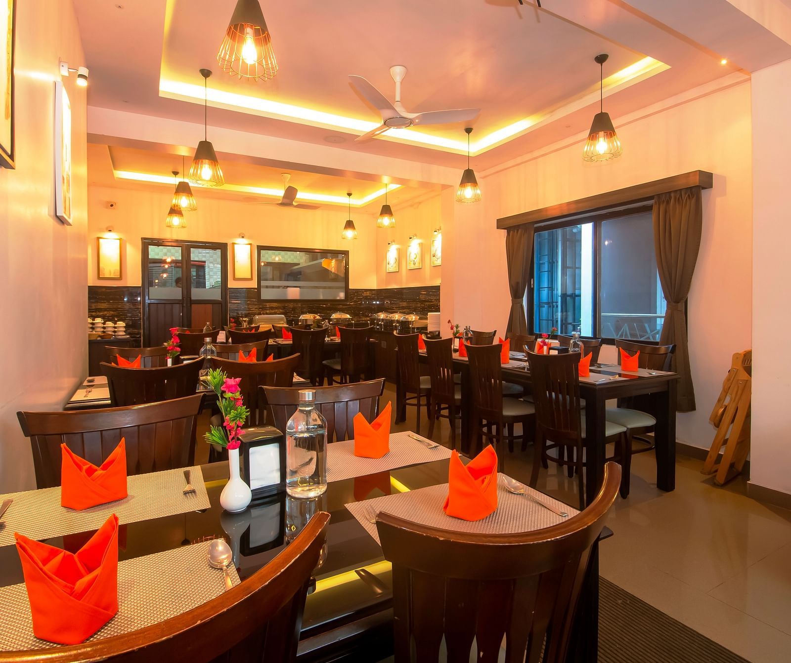 Image of a dining section with tables and chairs with lights hanging from the ceiling at Hotel Altitude, Madikeri.
