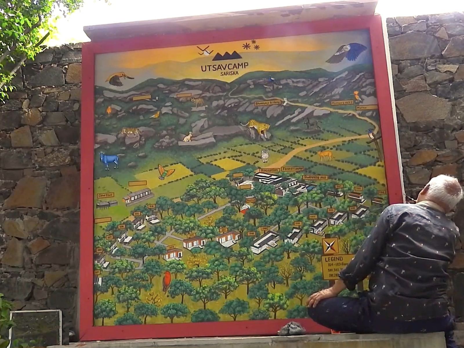 Artist painting the naturalist map at Utsav Camp Sariska on a large outdoor canvas.