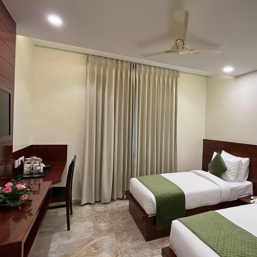 An image of two similar looking beds on a deluxe twin room which also features flat TV screen, a work desk and chair, and tea and coffee maker - Five Elements Hotel, Jodhpur