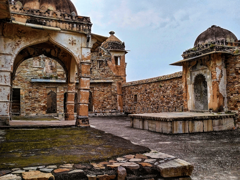 Arched gateway inside Chittorgarh Fort with stone pathways and weathered walls, highlighting layered construction and passageways leading through historic interiors