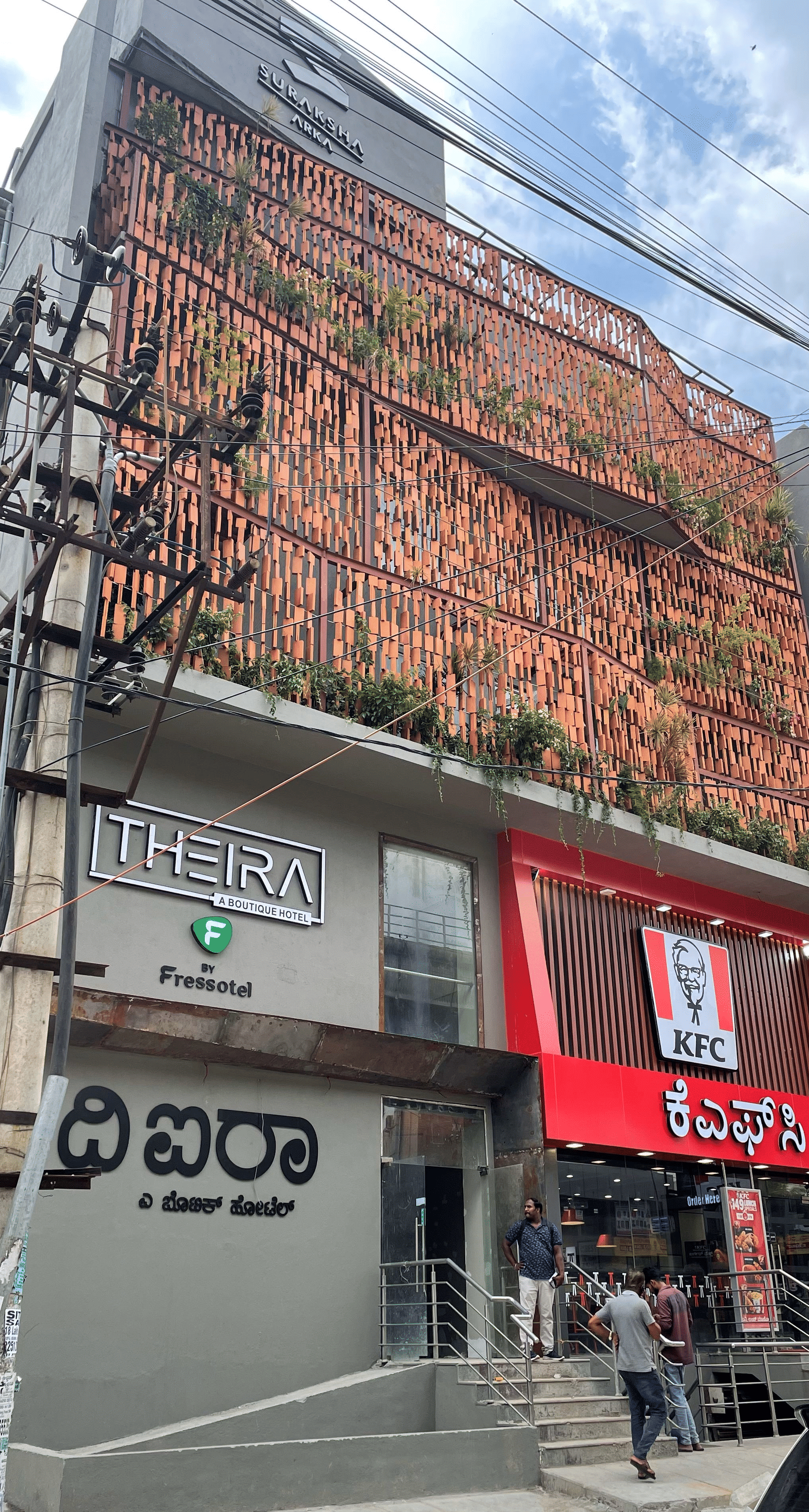 Facade image of Theira Fressotel, Bangalore with white clouds on blue sky in the background