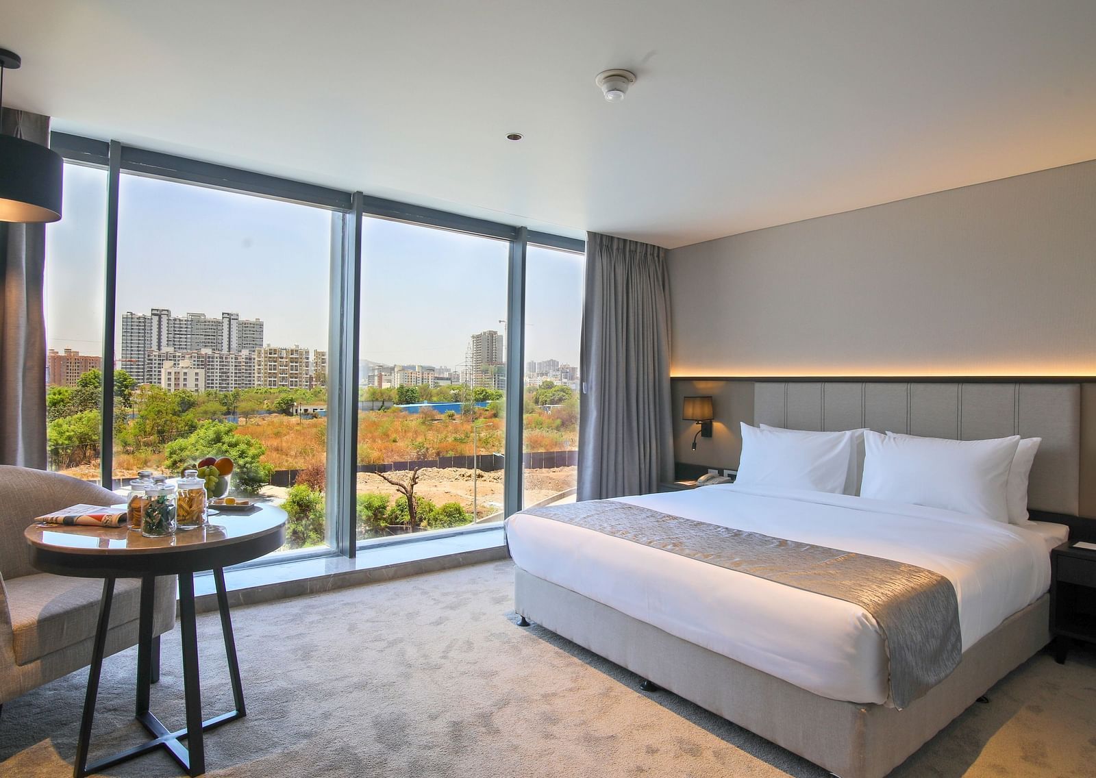 A double bed with a chair and table in front of it inside one of the rooms - Essentia Premiere, Pune