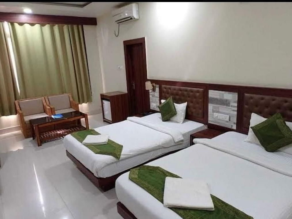 A twin room with white linen and green cushions, ideal for a comfortable and relaxed visit - Pemaling Lords Eco Inn Guwahati