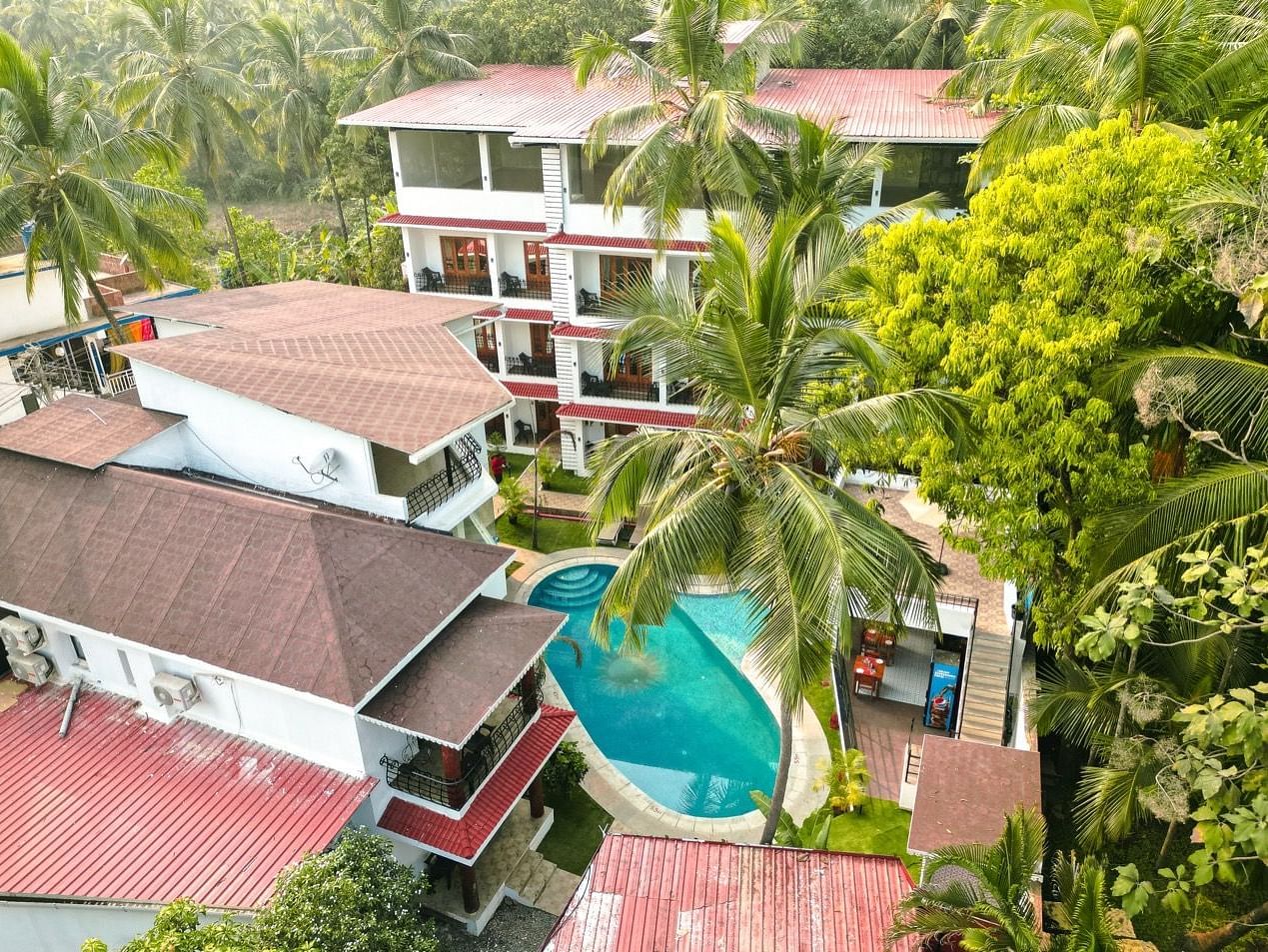 An aerial view of the The Verda de Miranda Resort nestled amidst palm trees, featuring multiple buildings and a turquoise pool.