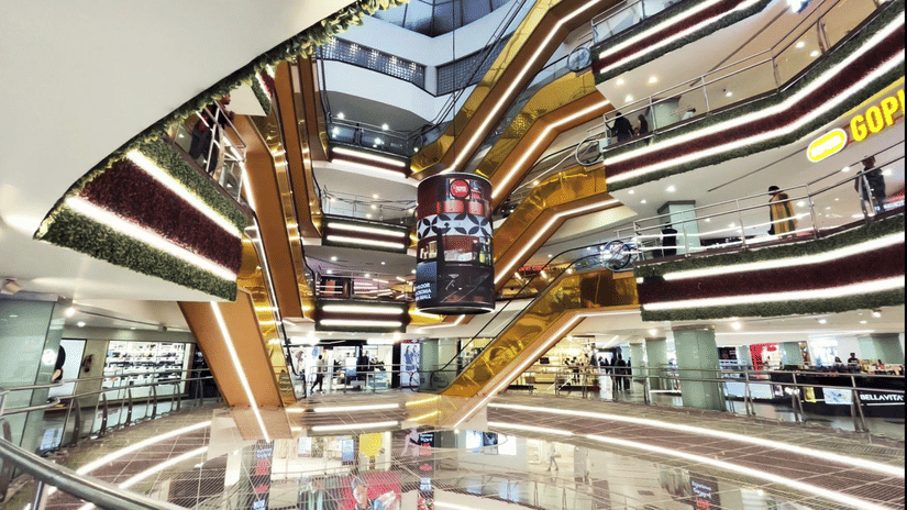 Multiple levels of escalators and brightly lit balconies frame the spacious central atrium area inside the modern interior of Garuda Mall.