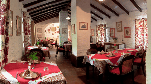 Seating arrangement inside a restaurant with aesthetic decor - Ramgarh Bungalows, Nainital.