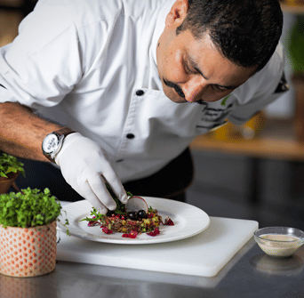 A chef plating a dish at Spice Route restaurant, rated for the best food in Ludhiana, inside Nirvana Luxury Hotel, Ludhiana.