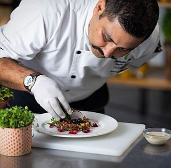 A chef plating a dish at Nirvana Luxury Hotel, Ludhiana.