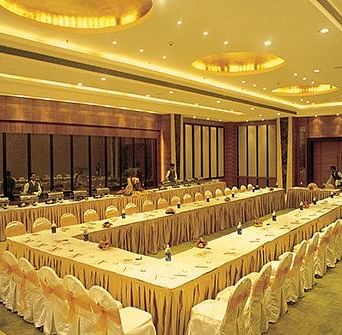 An event hall with multiple chairs surrounding a huge table at Nirvana Luxury Hotel, Ludhiana.