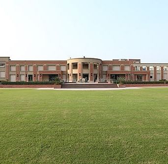 Facade view of Nirvana Luxury Hotel, Ludhiana with a garden in the front and clear blue sky in the background.