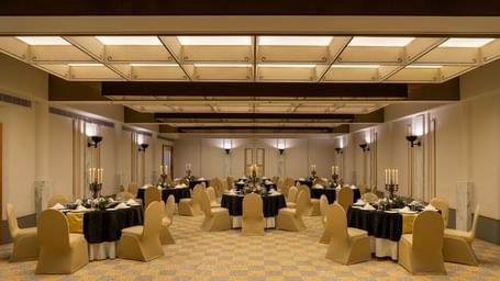  A banquet hall at Shilton International Kochi, set with numerous round tables and chairs, ready for an event.