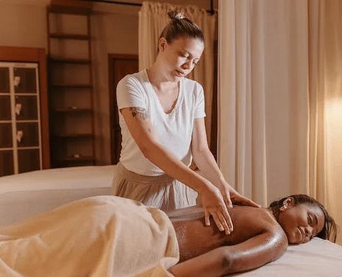 A professional therapist performing a soothing body massage on a content client in a softly lit, tranquil spa room.