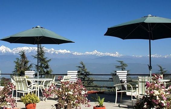 Outdoor dining area with tables and chairs on a balcony, overlooking a breathtaking mountain vista.