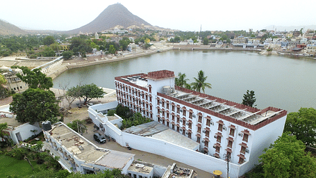 A drone shot of Hotel Pushkar Palace with a serene lake beside it