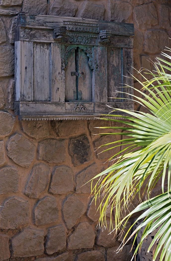 A close up shot of a wooden window with a plant below it - MANVAR Resort & Desert Camp