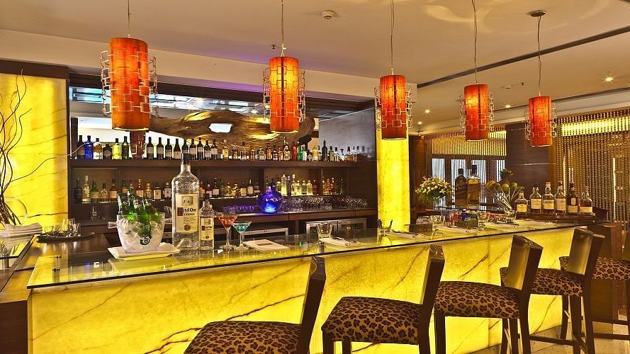 Elegant bar with illuminated counter, warm lighting, and premium liquor selection – Hotel Hindusthan International, Kolkata.