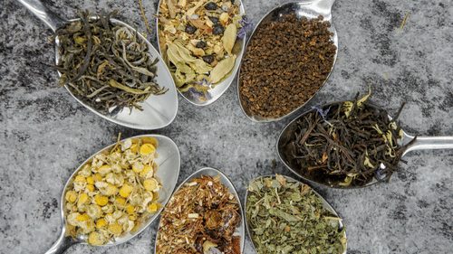 seven spoons containing different spices 