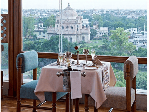 An Awadhi Rooftop Restaurant in Lucknow by a window with a view of a city monument, representing a lavish stay in Lucknow experience at Clarks Avadh, Lucknow.