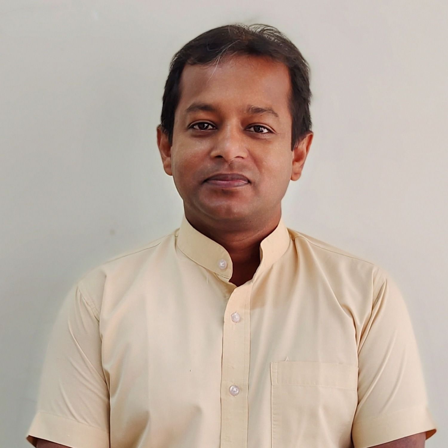 A man in a light-coloured shirt looks directly at the camera