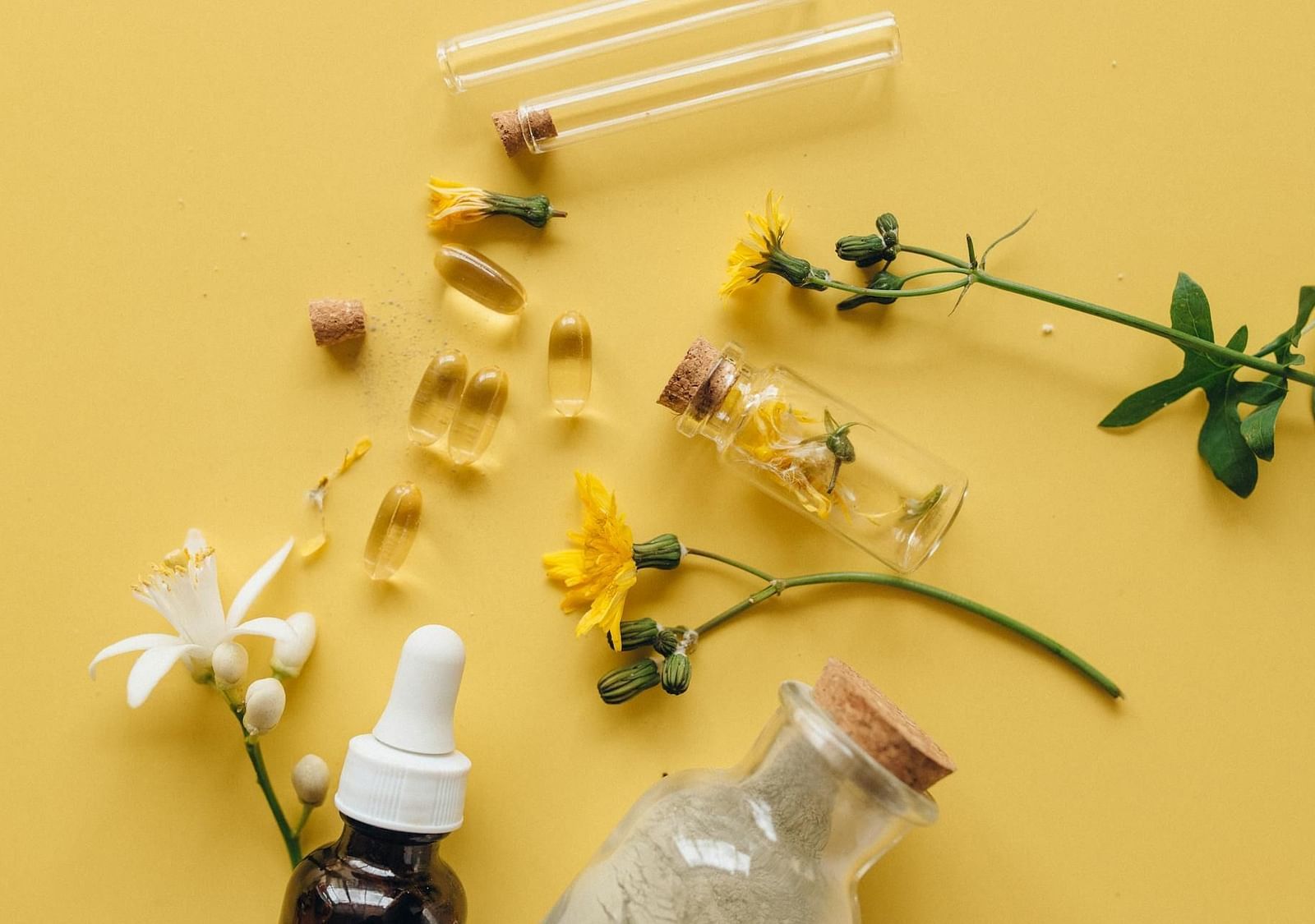 Essential herbs, flowers, and oils arranged on a plain background