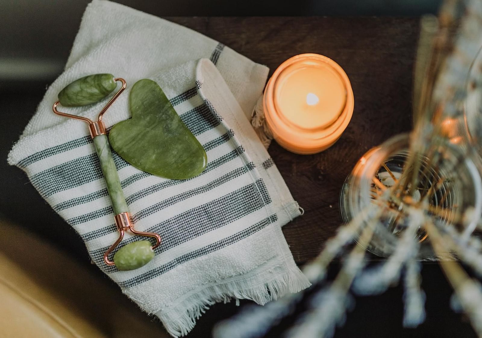 Gemstone face massage tools, a lit candle, and burning incense in a spa