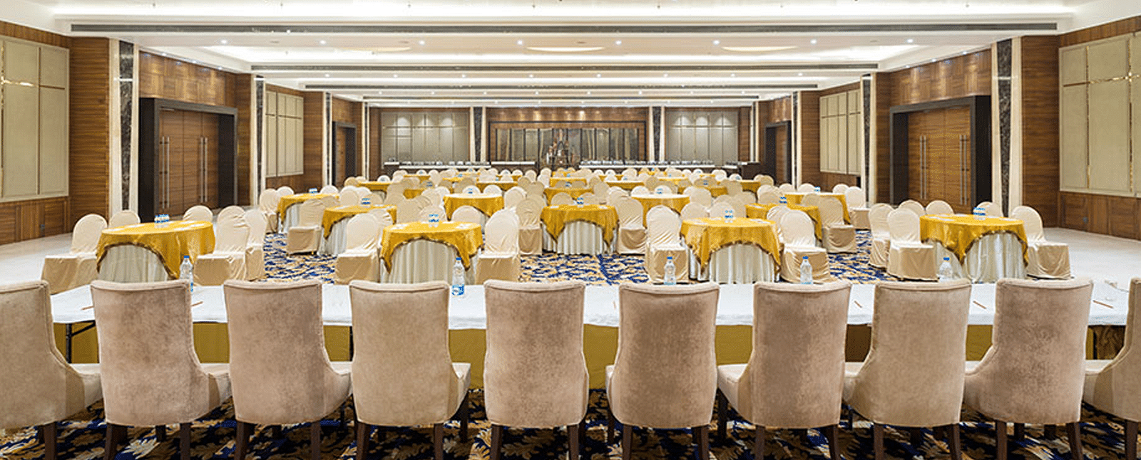 An event hall with white chairs facing towards the podium at Nirvana Luxury Hotel, Ludhiana.