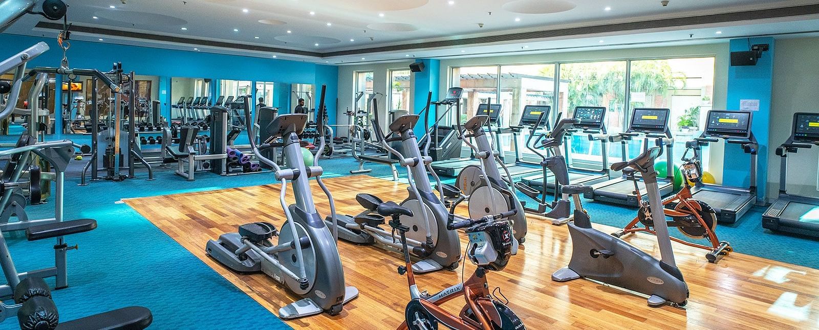 Indoor gym at Nirvana Luxury Hotel, Ludhiana with training equipment and blue interiors