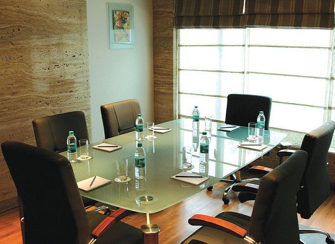 Image of a meeting room at our hotel featuring a glass table with seven chairs around it. | Mirage Hotel