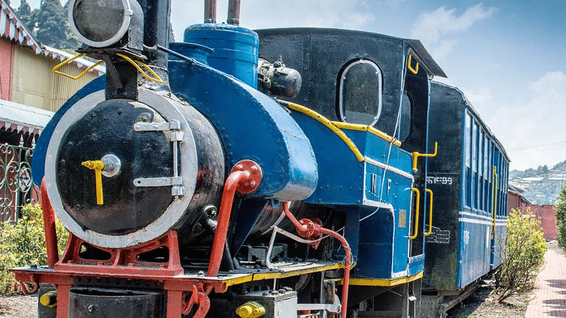 Close up view of a toy train engine on railway tracks, with visible front detailing and surrounding station elements.