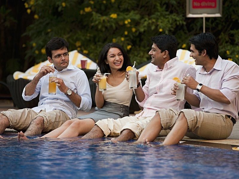 a group of people relaxing by the pool with drinks in their hands