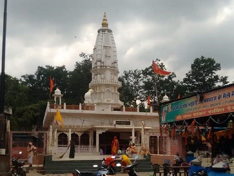 Bhartrihari Temple with a tall tower stands against a cloudy sky.