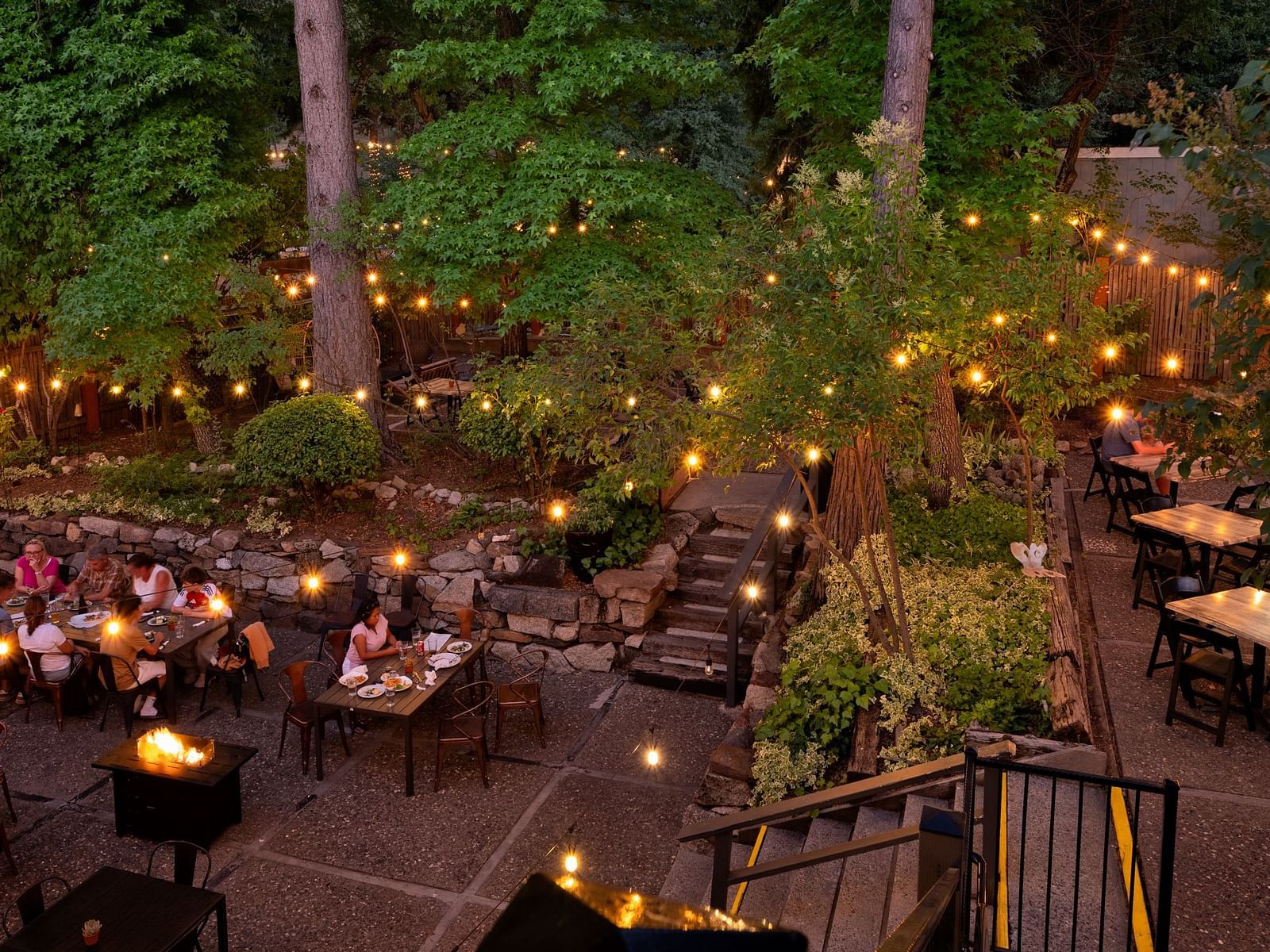 Outdoor evening dining area with guests enjoying a meal under string lights at The Groveland Hotel.